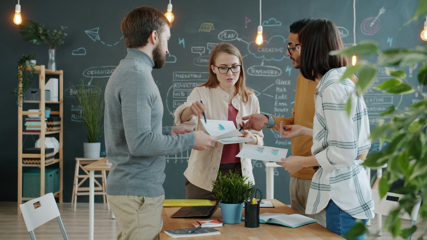 Geschäftsteam berät sich an einem Tisch mit Diagrammen und Grafiken.